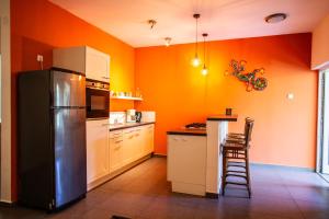 a kitchen with orange walls and a black refrigerator at CocoCasa 22 Stylish Luxury Apartment with Pool near Jan Thiel Beach in Willemstad