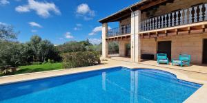 a swimming pool in front of a house with two blue chairs at Maravillosa finca con piscina in Marratxi
