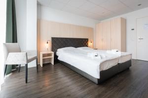 a bedroom with a large white bed and a chair at Los Lorentes Aparthotel Bern Airport in Belp