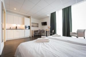 une chambre d'hôtel avec deux lits et une cuisine dans l'établissement Los Lorentes Aparthotel Bern Airport, à Belp