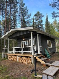 a small house with a large deck in the woods at Kenttäpirtti in Kittilä