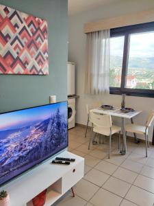 a living room with a large flat screen tv and a table at CityZEN View - Retro Nest in Argostoli