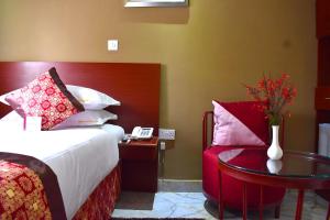 - une chambre avec un lit, une table et un téléphone dans l'établissement Perla Hotel, à Kampala