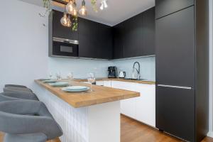 a kitchen with black cabinets and a wooden counter top at Ślusarska Modern Apartment with Balcony & Parking Cracow Zabłocie by Renters Prestige in Krakow