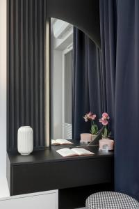 a bathroom with a vanity with a mirror and flowers at Ślusarska Modern Apartment with Balcony & Parking Cracow Zabłocie by Renters Prestige in Krakow