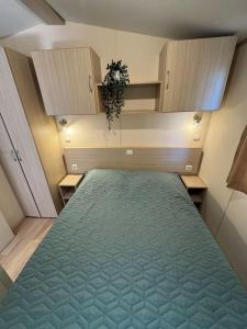 une chambre avec un grand lit avec une couverture verte dans l'établissement Mobilhome 3 chambres 6 personnes près de la plage - Novela - Frédéric et Sandra, à Port-la-Nouvelle