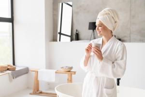 a woman standing in a bathroom holding a cup of coffee at Aberdunant Hall in Porthmadog