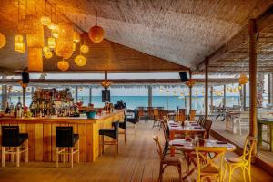 a restaurant with a bar and tables and chairs at Alaçatı Beach Resort in Yumru