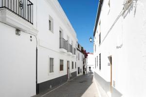 eine Gasse mit weißen Gebäuden und einem blauen Himmel in der Unterkunft Apartamento María Conil Bajo in Conil de la Frontera