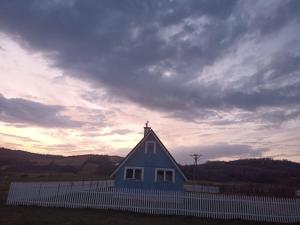 a blue house with a white fence in a field at U Ewy pod Brzozami in Nowy Żmigród