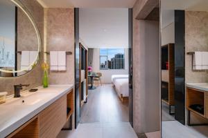 a bathroom with a sink and a bedroom with a bed at UrCove by HYATT Shanghai Jing'An in Shanghai