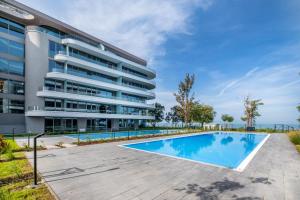 un immeuble d'appartements avec une piscine en face dans l'établissement MF Wave Botanic Apartment, à Siófok