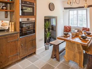 a kitchen with a wooden table and a counter at Thorn Cottage Winsford in Winsford