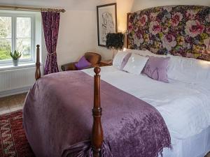 a bedroom with a large bed with a floral headboard at Thorn Cottage Winsford in Winsford