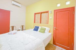 1 dormitorio con cama blanca y puerta roja en Urbanview Hotel Sany Cirebon en Tangkil