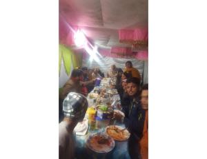 a group of people sitting at a long table eating food at River Front Guest House Aru Pahalgam in Anantnāg