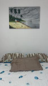 una pintura de una playa y una cama con almohada en Casa Aeroporto Maceió Palmeiras, en Maceió