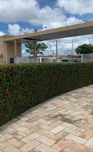 a hedge with red flowers in front of a building at Casa Aeroporto Maceió Palmeiras in Maceió