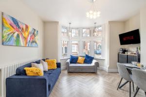 a living room with a blue couch and two chairs at Comfortable flat by MT Property in Nottingham