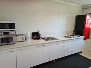 uma cozinha com armários brancos, um micro-ondas e um lavatório em Orchard 2 Bedroom Apartment in Devonport 