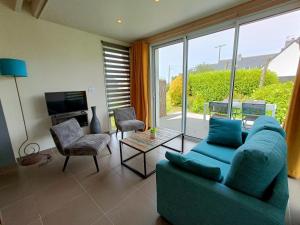 Una sala de estar con un sofá azul y una ventana grande. en Les Gîtes du Pêcheur, en Erquy