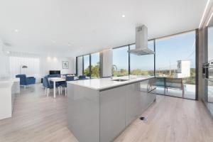 a kitchen and dining room with white cabinets and glass windows at Villa Natureza - By SCH in Serra do Bouro
