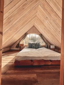 a bed in a room with a wooden ceiling at Chatka Biesczadersko in Lutowiska