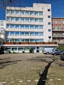 un grand bâtiment blanc avec des voitures garées devant lui dans l'établissement Court Garden Hotel - Ecodesigned, à La Haye