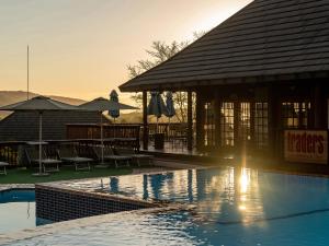 哈玆維尤的住宿－哈斯美景小屋旅館，一个带游泳池、桌子和遮阳伞的度假村