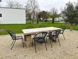 un tavolo in legno con quattro sedie intorno di L'émeraude - Avec jardin a Lagord