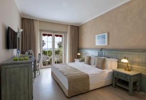 a bedroom with a large bed and a balcony at Alaçatı Beach Resort in Yumru