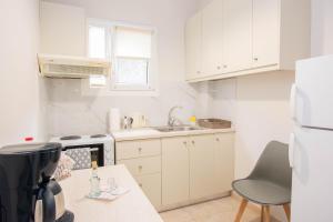 a small kitchen with white cabinets and a sink at Traveller's Nest Apartment close to center,port,airport in Heraklio Town