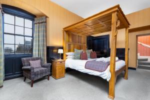 a bedroom with a canopy bed and a chair at Dornoch Castle Hotel in Dornoch