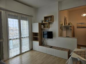 - un salon avec une télévision et une grande fenêtre dans l'établissement La Casetta di Noi2, à Spotorno