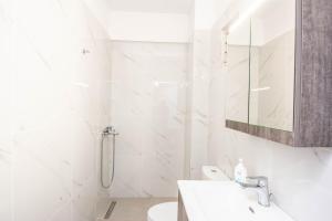 een witte badkamer met een wastafel en een douche bij Traveller's Nest Studio close to center,port,airport in Heraklion