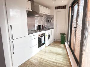 a kitchen with white appliances and a wooden floor at The Works - Two bed penthouse in Manchester