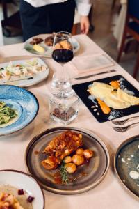 uma mesa com pratos de comida e um copo de vinho em Hotel Le Grotte em Genga