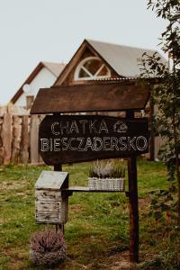 a sign in a field with a house in the background at Chatka Biesczadersko in Lutowiska