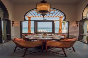 ein Esszimmer mit einem Tisch und Stühlen sowie einem großen Fenster in der Unterkunft Naama Beach Villas & Spa in Al Aqah