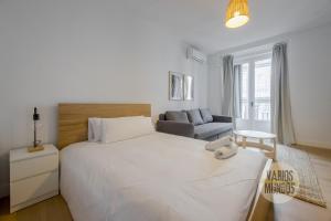 a bedroom with a large white bed and a couch at Comodo y centrico Loft en calle Carretas - Madrid Centro in Madrid