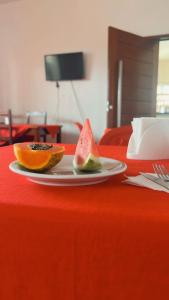 a plate with two slices of fruit on a red table at Pousada Girassol in Maceió