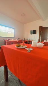 a red table with a plate of fruit on it at Pousada Girassol in Maceió