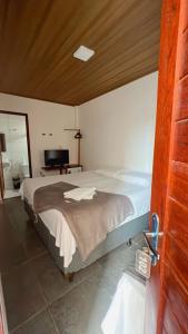 - une chambre avec un grand lit et une télévision dans l'établissement Pousada Girassol, à Maceió