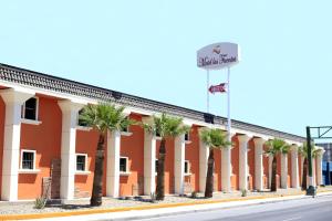 a building with palm trees in front of a street at Motel Las Fuentes in Mexicali