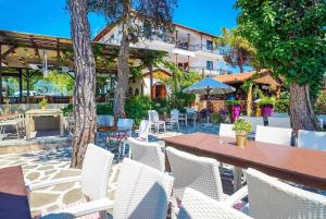 un patio con sillas blancas, mesa y árboles en Thassos ESPERIA HOTEL en Pefkari