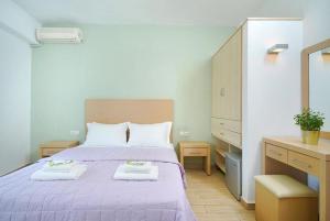 a bedroom with a purple bed with two towels on it at Thassos ESPERIA HOTEL in Pefkari