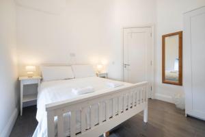 a white bedroom with a white bed and a mirror at Parliament Street Town House in Ennistymon