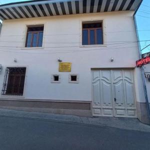 um edifício branco com duas portas de garagem numa rua em Yusuf Gold House em Samarkand