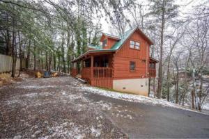 a red house with a driveway in the woods at A Charming Cabin, Pool, Firepit, Hot Tub-jacuzzi in Gatlinburg