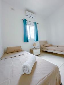 um quarto branco com 2 camas e cortinas azuis em Lovely flat close to St julians with 6 beds in 3 rooms for 8 people em Is-Swieqi